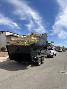A GO Disposal Roll Off Services truck hauling a trailer full of yard waste in El Paso, TX, demonstrating general junk removal.