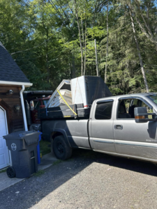 A junk removal truck loaded with dismantled shed debris backed up to a residential garage by Trash Hogs in Worcester, MA.
