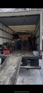 A HaulPros truck being loaded with various junk items using a ramp, indicating a removal job in Erie, PA.