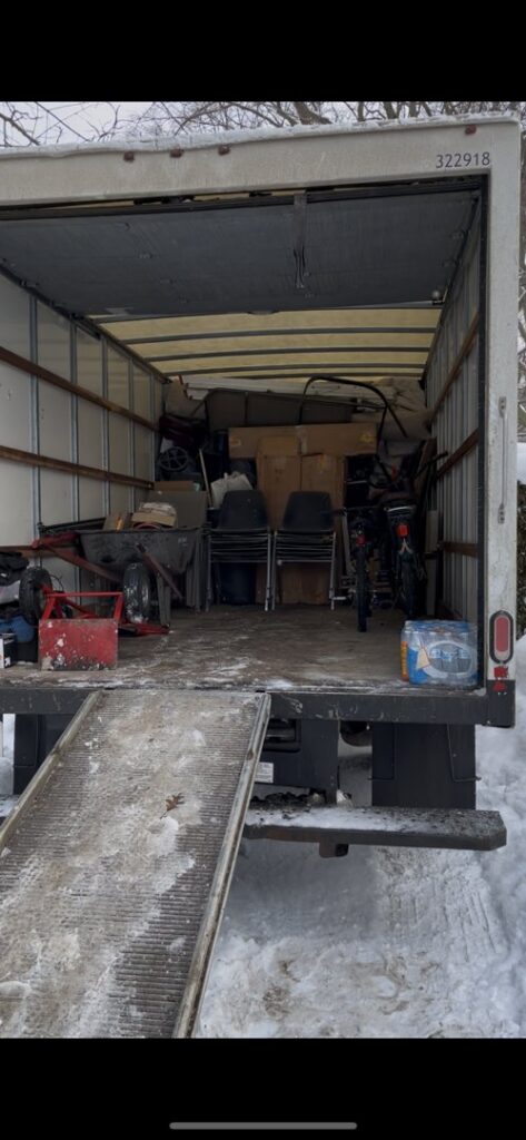 A HaulPros truck being loaded with various junk items using a ramp, indicating a removal job in Erie, PA.