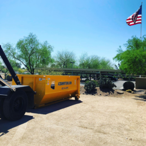 A truck moving a yellow dumpster in an outdoor setting for AZ Dumpster Rentals junk removal in Surprise, AZ
