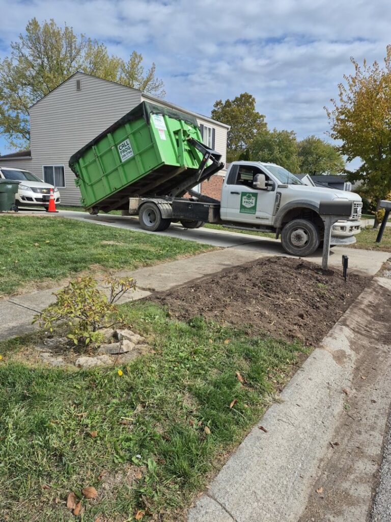 A Frog Hauling truck picking up a green dumpster from a residential driveway in Columbus, OH.
