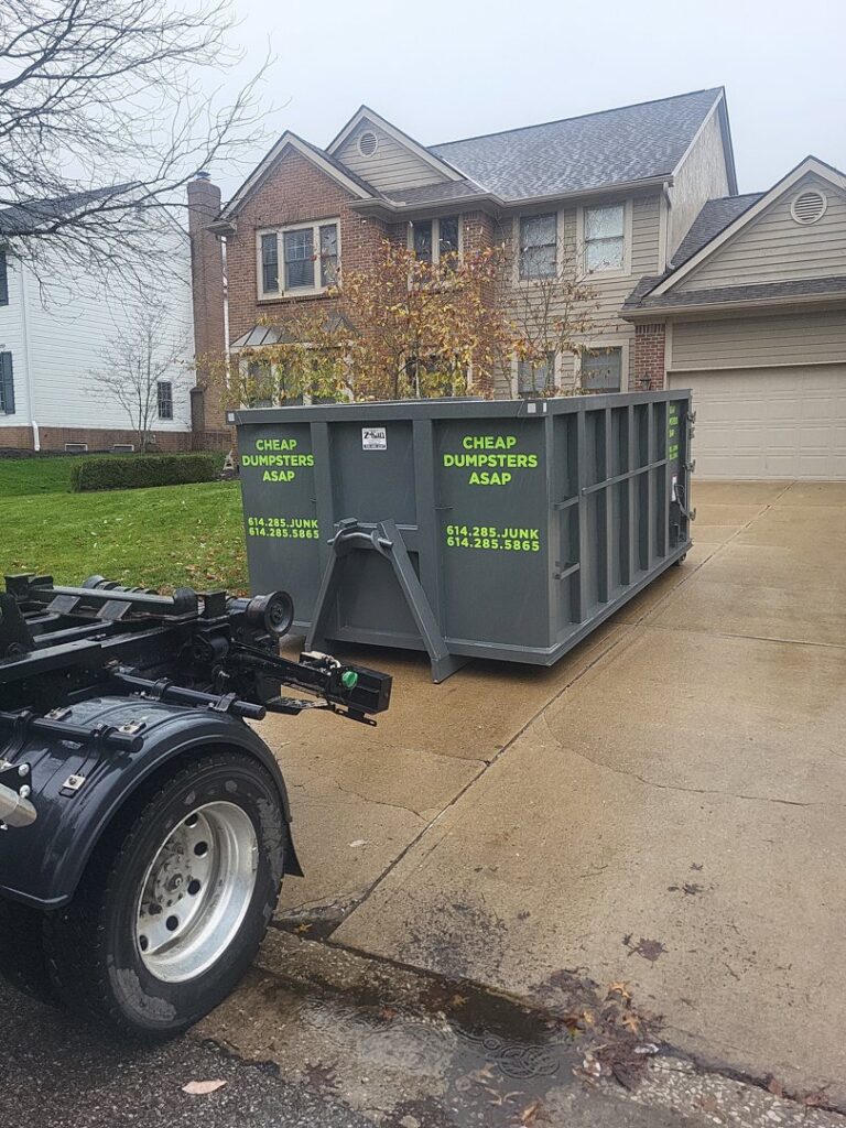 A truck backing up to place a dumpster in a residential driveway for junk removal by Cheap Dumpsters ASAP in Columbus, OH.