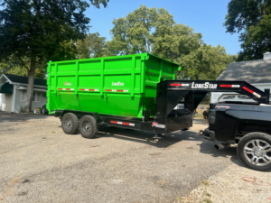 A truck pulling a green dumpster trailer in a residential neighborhood for Proper Dumpster Rentals in Kansas City, KS.