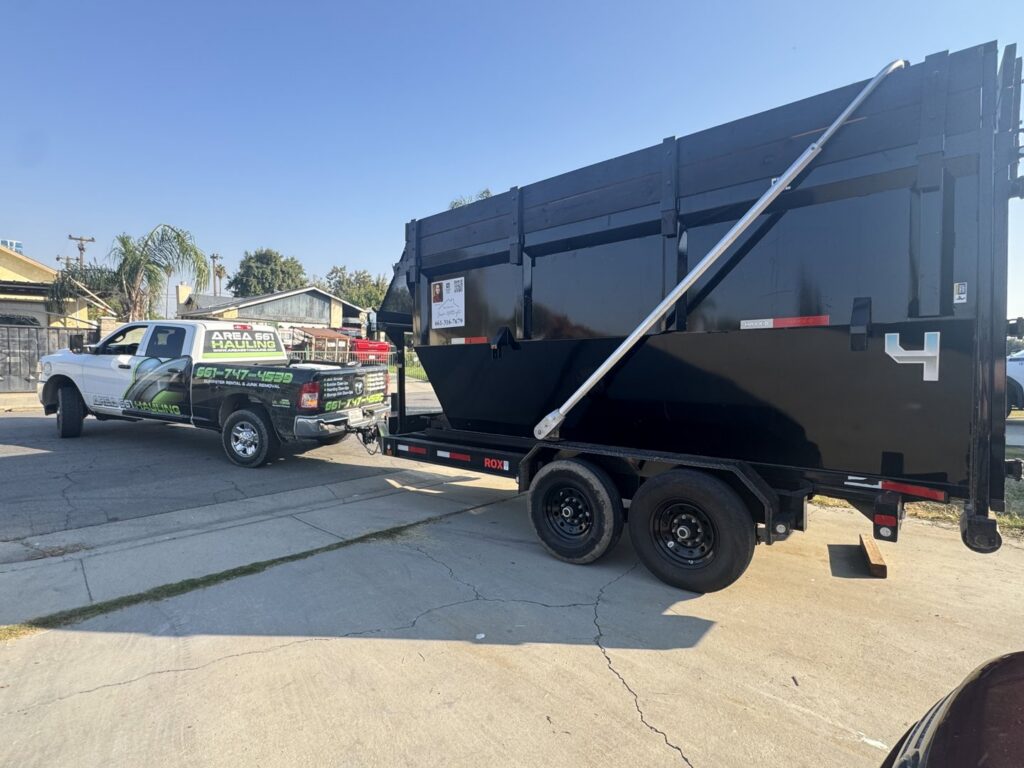 A branded truck from Area 661 Hauling pulling a large black dump trailer, ready for a junk removal job in Bakersfield, CA.
