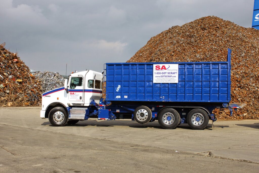 A truck with a large blue roll-off container for scrap metal at SA Recycling - Long Beach Ave in Los Angeles, CA.