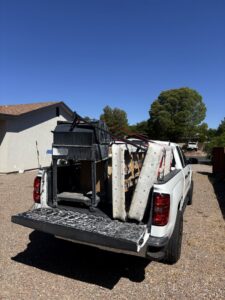 A richartehelps pickup truck with its tailgate down, loaded with a grill, cushions, and other junk for removal in Scottsdale, AZ.