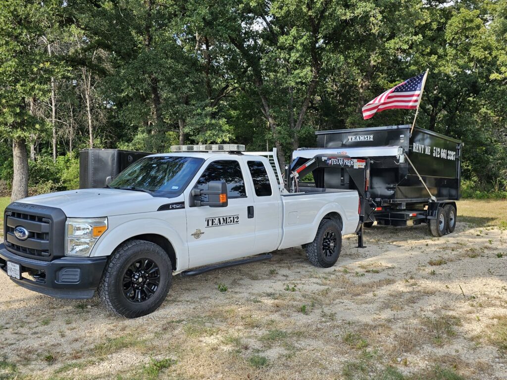 A Team512 truck towing a dumpster trailer with 'RENT ME' signage and an American flag in Austin, TX