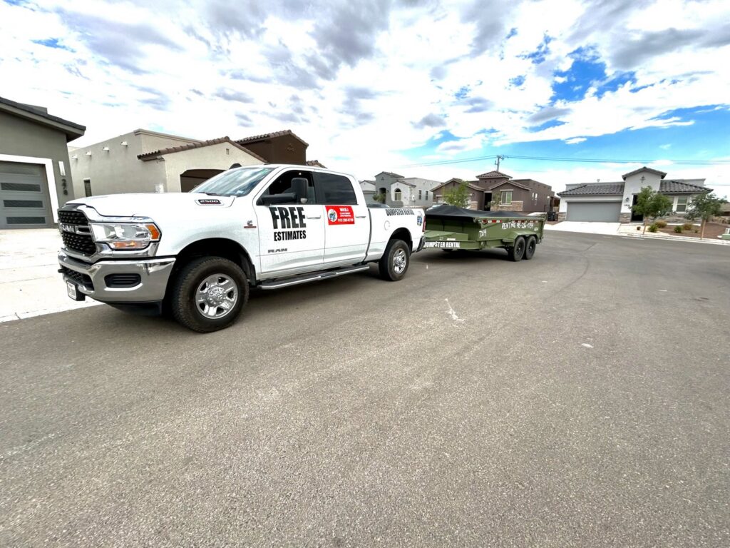 A truck from Easy Load Disposal El Paso towing a green dump trailer through a residential neighborhood in El Paso, TX.