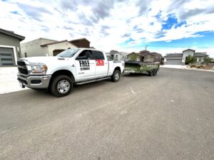 A truck from Easy Load Disposal El Paso towing a green dump trailer through a residential neighborhood in El Paso, TX.