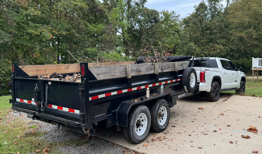 A pickup truck towing a dump trailer filled with yard waste and branches for Trash & Dash in Houston, TX.