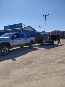 A Valley Haul Off LLC truck and dump trailer at a recycling facility, disposing of collected junk in Visalia, CA.