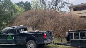 A JP'S Tree Service truck with a trailer full of brush and branches after a tree clearing job in Austin, TX.