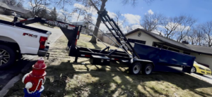A truck and trailer delivering a blue dumpster for Great Lakes Bins in South Bend, IN, for junk removal services.