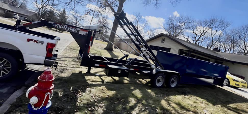 A truck and trailer delivering a blue dumpster for Great Lakes Bins in South Bend, IN, for junk removal services.