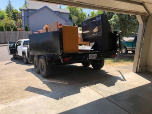 A truck with a trailer full of removed junk and debris in a residential driveway by LNK Junk Removal in Council Bluffs, IA.