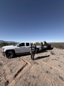 A white pickup truck with a black utility trailer hauling large items, demonstrating junk removal services by richartehelps in Scottsdale, AZ.