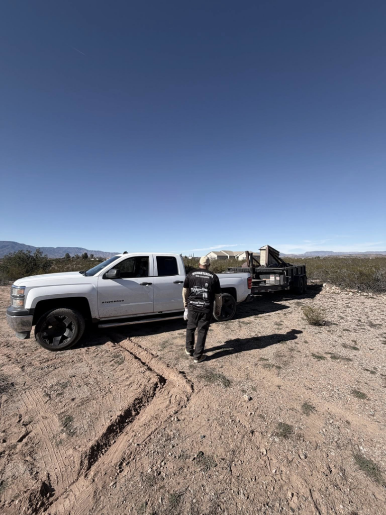A white pickup truck with a black utility trailer hauling large items, demonstrating junk removal services by richartehelps in Scottsdale, AZ.