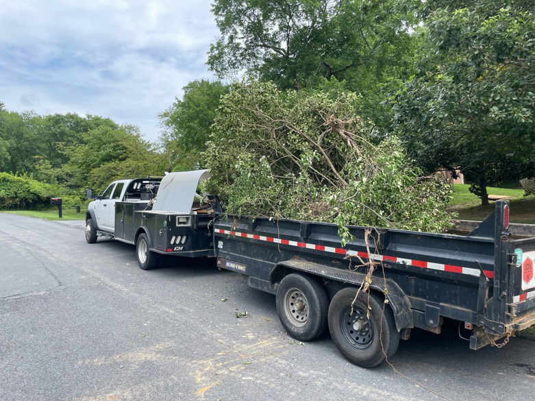 A work truck towing a trailer full of tree branches and yard waste by JDS Home Improvement in Gaithersburg, MD.