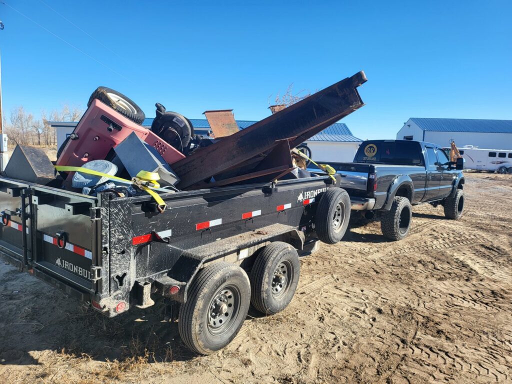 A pickup truck pulling a dump trailer loaded with heavy metal and construction debris by Rubble Removers LLC in Riverton, WY.
