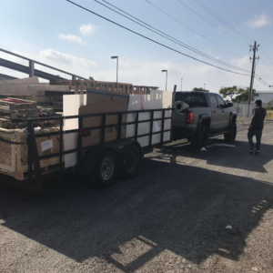 A truck with a trailer loaded with construction debris and large items for removal by CC JUNK Removal in Corpus Christi, TX.