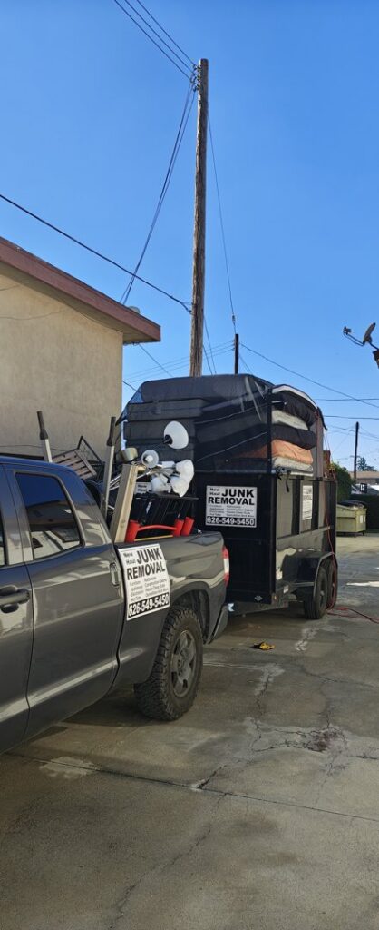 A New Haul Junk Removal truck and trailer loaded with mattresses and various junk items in Los Angeles, CA.