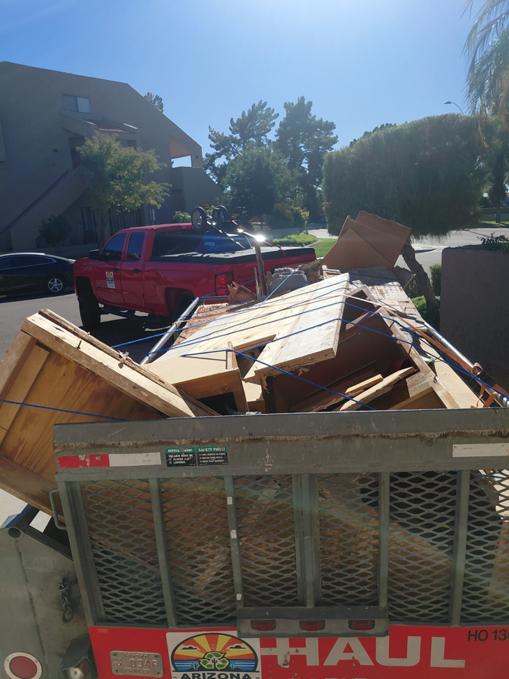 A truck and trailer loaded with junk and debris, featuring the Arizona Junk Removal LLC logo, in Phoenix, AZ