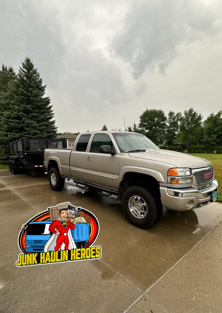 A Junk Haulin Heroes truck pulling a trailer loaded with various items of junk for removal in Bismarck, ND.