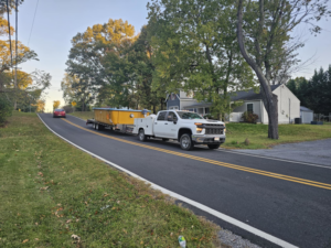 A pickup truck transporting a yellow composite pool shell for installation by Composite Pools USA in Newfield, NJ.