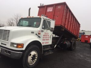 A white truck with a red roll-off dumpster, branded B & B Refuse Inc, for junk removal in Rockville, MD.