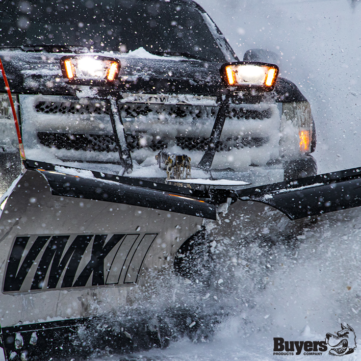 A truck equipped with a snow plow actively clearing a snowy road, a service supported by Handyman Vehicle Outfitters in Portland, ME.