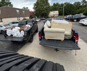 Two pickup trucks loaded with bags of trash and old furniture for removal by Junk Hawgs Removal and Rentals in Russellville, AR.