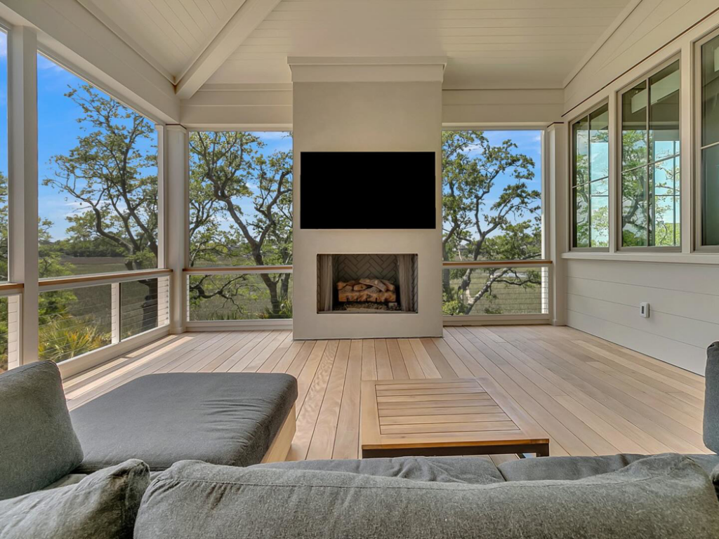 A flat-screen TV professionally mounted above a fireplace on an outdoor porch by Mahshie Custom Homes in Charleston, SC.