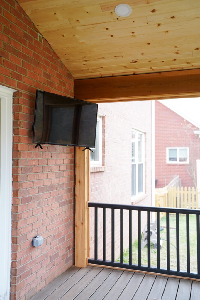 A television mounted on a brick wall of a newly built screened porch by Vision Construction in Framingham, MA.
