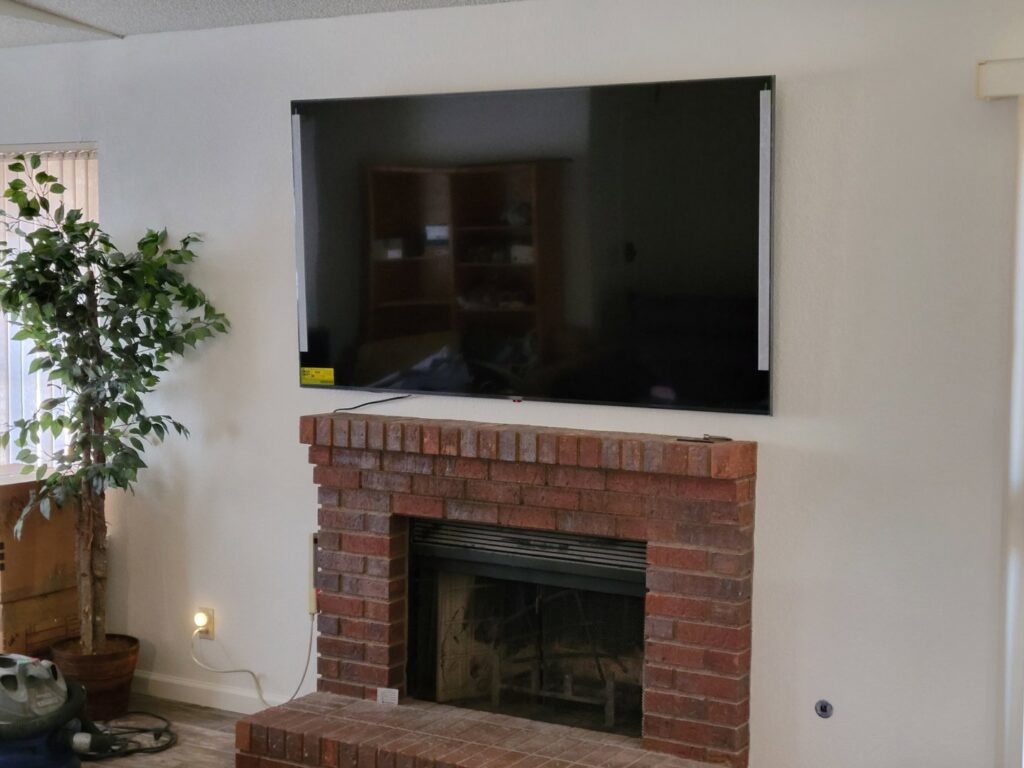A large television professionally mounted above a brick fireplace by McCarran Handyman Services in Boulder City, NV.