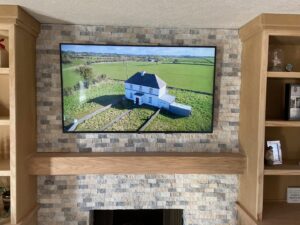 A flat-screen TV professionally mounted above a stone fireplace by Titan Handyman Services in Lewes, DE