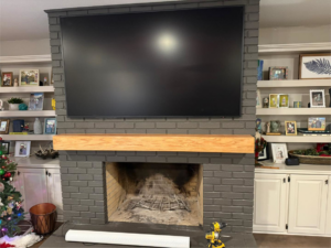 A large TV mounted above a newly installed wooden mantel by Profix Home Repair in Jonesboro, AR.