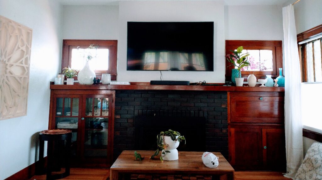 A flat-screen TV professionally mounted above a brick fireplace in a living room by Boise Handyman & Remodel in Boise, ID.