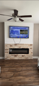 A newly mounted TV above a fireplace with shiplap and stone veneer, completed by M&M Handyman Services LLC in Clarksville, TN.