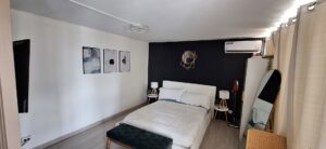 A bedroom featuring a wall-mounted TV and multiple floating shelves installed by Just-In-Time Handyman Services in Honolulu, HI.