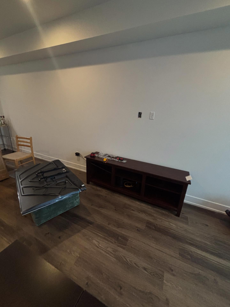 Before photo of a TV mounting service by Grade A Handyman in Lancaster, CA, showing the TV on the floor.