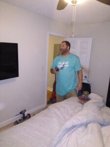 A handyman standing in a bedroom after completing a TV mounting service for Holy City Remodel in North Charleston, SC.