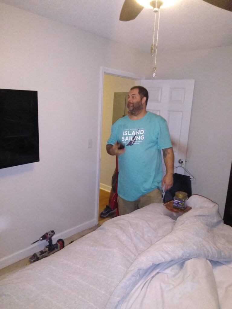 A handyman standing in a bedroom after completing a TV mounting service for Holy City Remodel in North Charleston, SC.