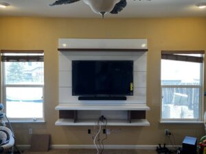 A wall-mounted TV on a custom white and wood media unit with shelves, installed by Prospective 1, LLC in Sparks, NV.