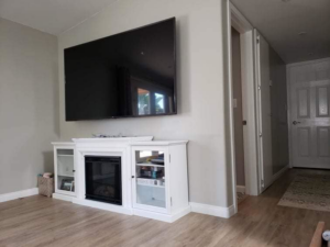 A large TV professionally wall-mounted above a white fireplace console, a service provided by NH Handyman in San Diego, CA.