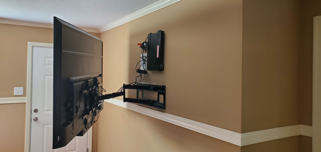 A large television being mounted on a wall, showing the bracket and wiring, by Walnut Bridge Construction in Knoxville, TN