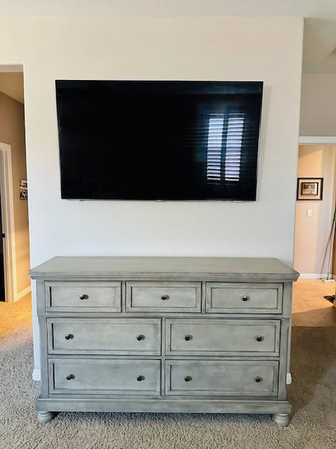A flat-screen television professionally mounted on a wall above a dresser by Henderson Handyman in Henderson, NV
