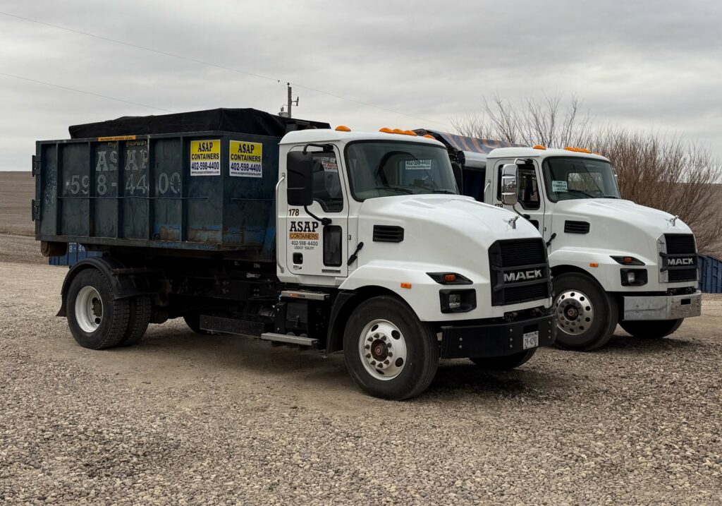 Two ASAP Containers inc. trucks with blue dumpsters parked, ready for junk removal services in Omaha, NE.