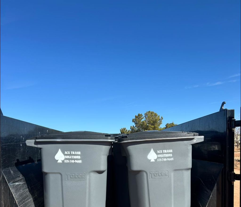 Two branded trash bins from Ace Trash Solutions loaded in a truck, ready for junk removal in Las Cruces, NM.