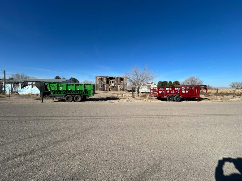 Two dump trailers from Easy Load Disposal El Paso parked at a junk removal site with old structures in El Paso, TX.